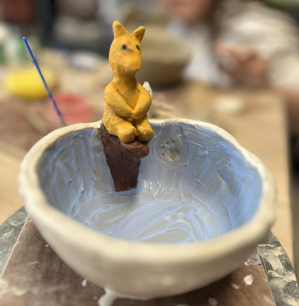 Un bol façonné à la main avec une figurine sculpté d'un renard qui se prépare pour un plongeon dans le bol -piscine.