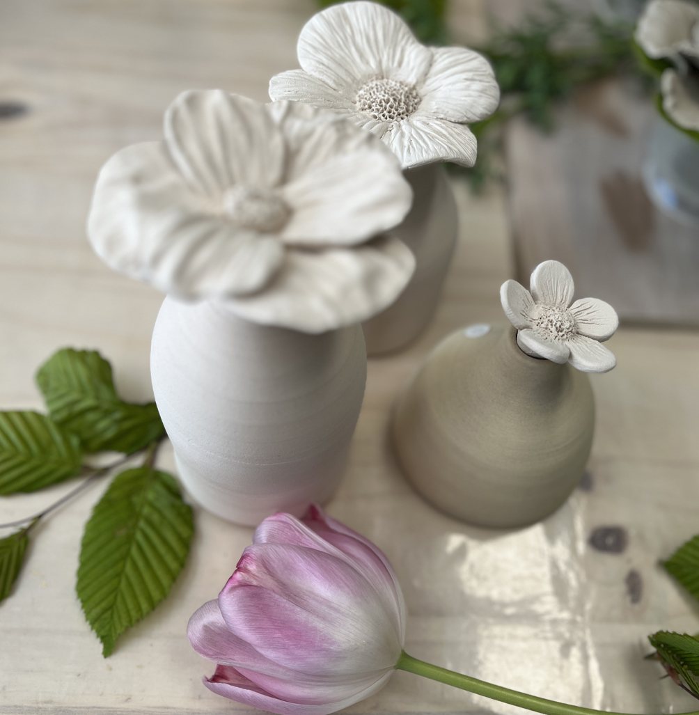 des vases en terre cuites faites au tour et décorés par des fleurs en céramique façonnées à la main