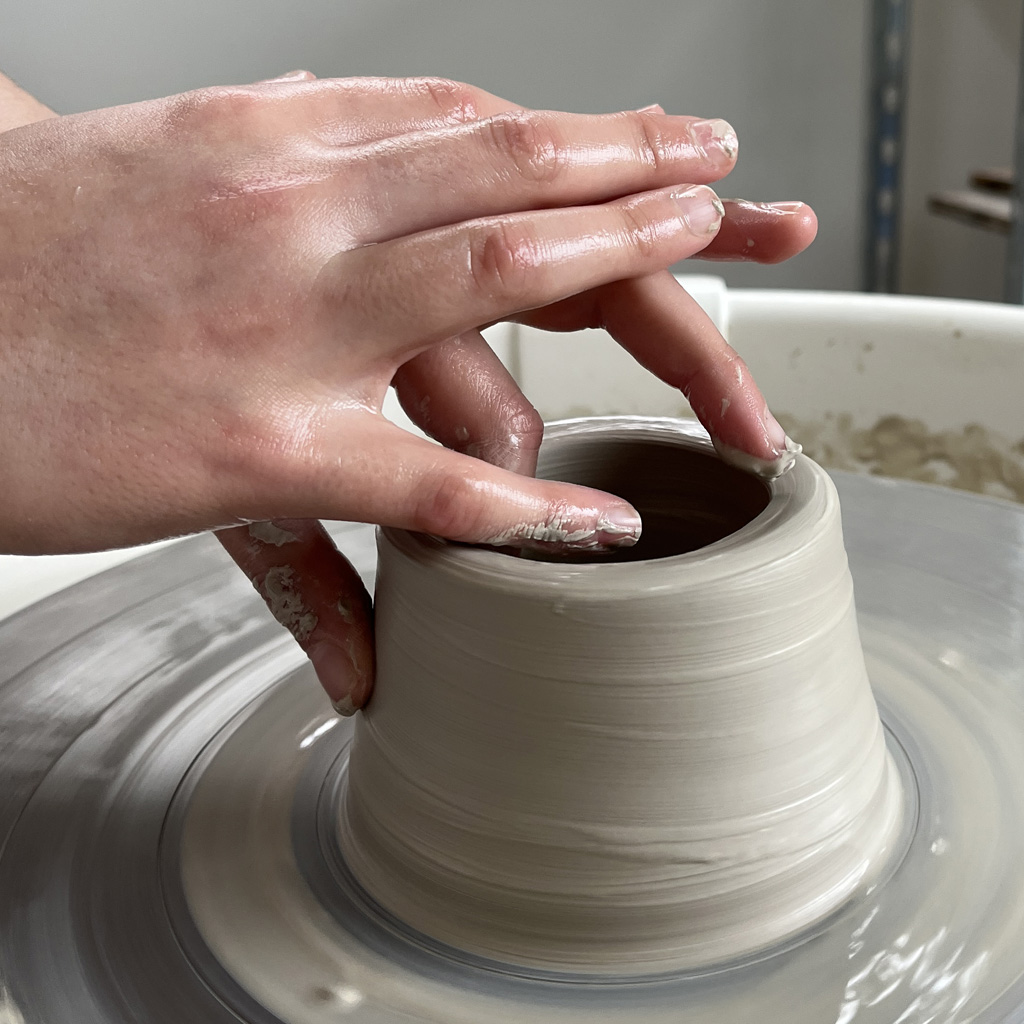 les mains sur l'argile en train de façonner un objet sur le tour de potier à l'atelier ciel-sur-terre-a-sars-et-rosieres