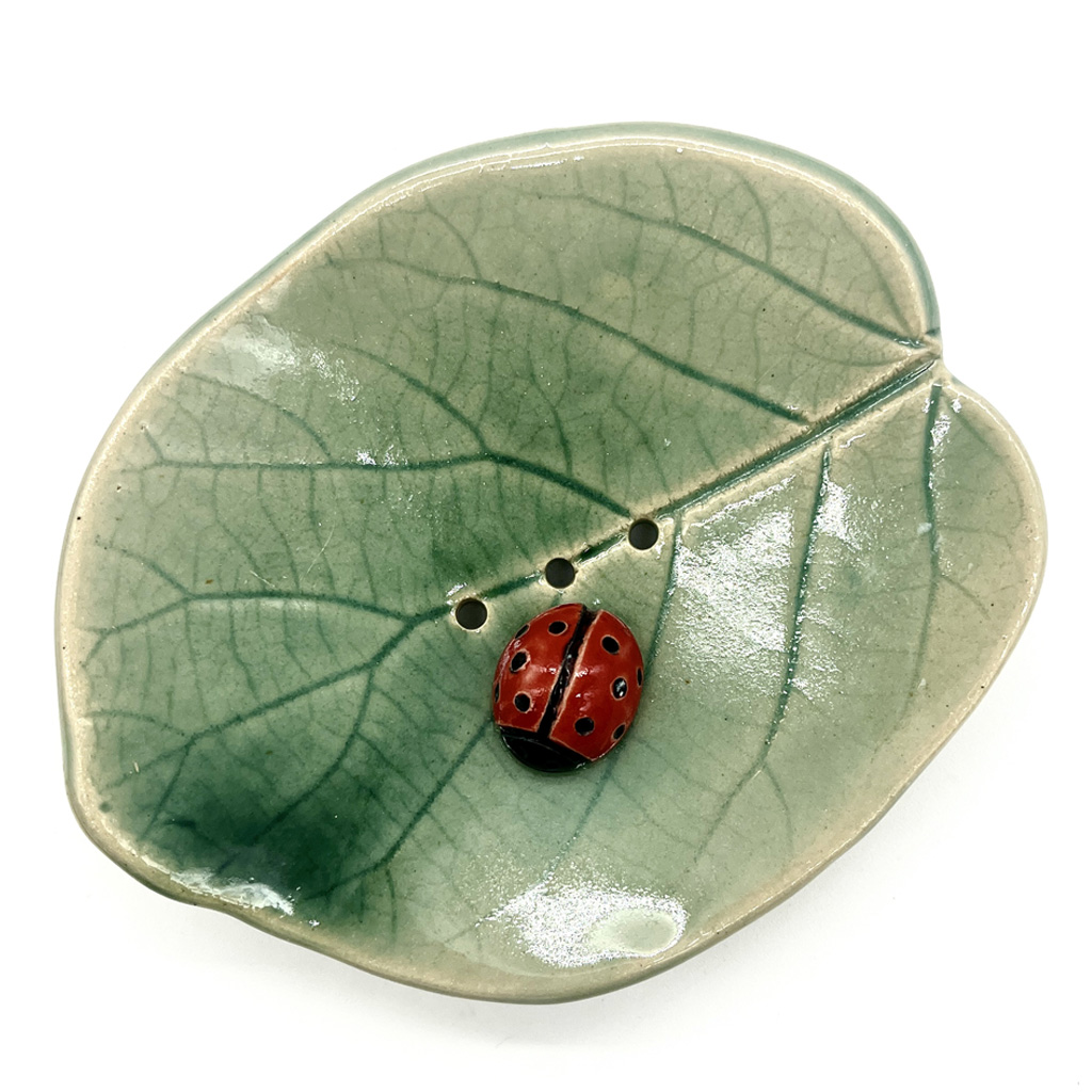 un porte savon en forme d'une feuille avec une petite coccinelle assise dessus en céramique artisanale